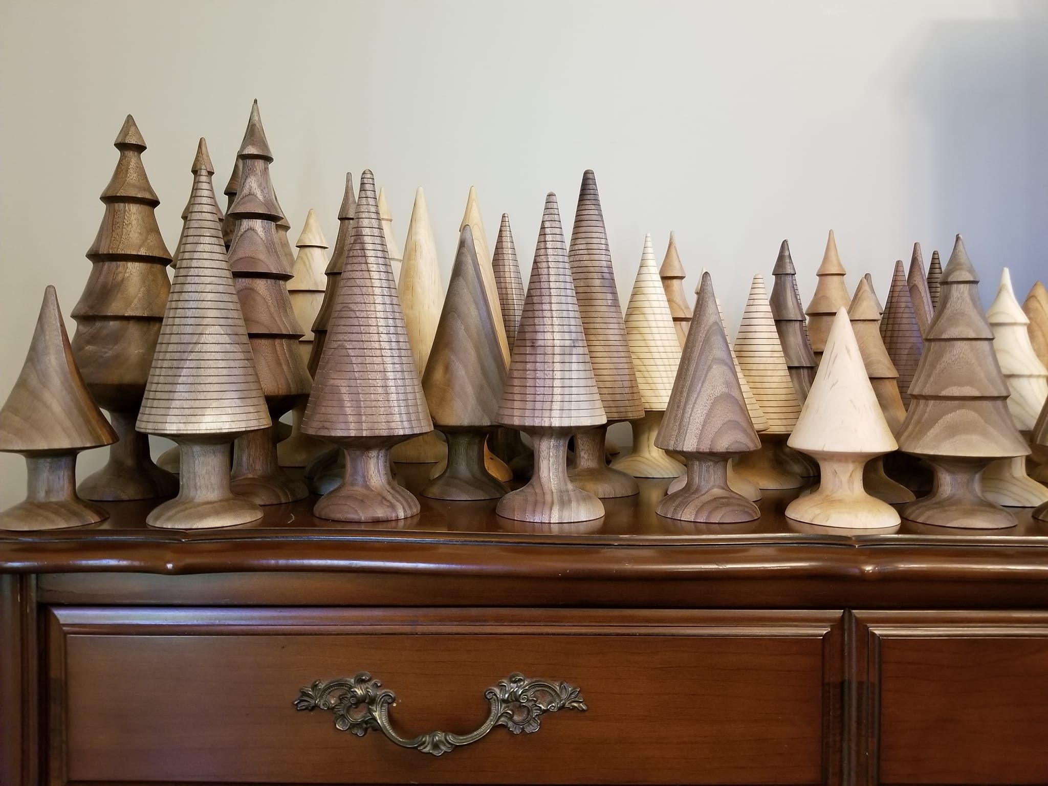 A forest of hand-turned walnut and maple decorative trees on a dresser